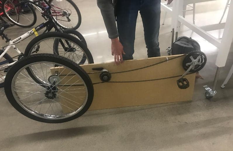 A wheel, chain, and crank mounted on a cardboard panel as a mockup of foot propulsion with back-pedal braking.